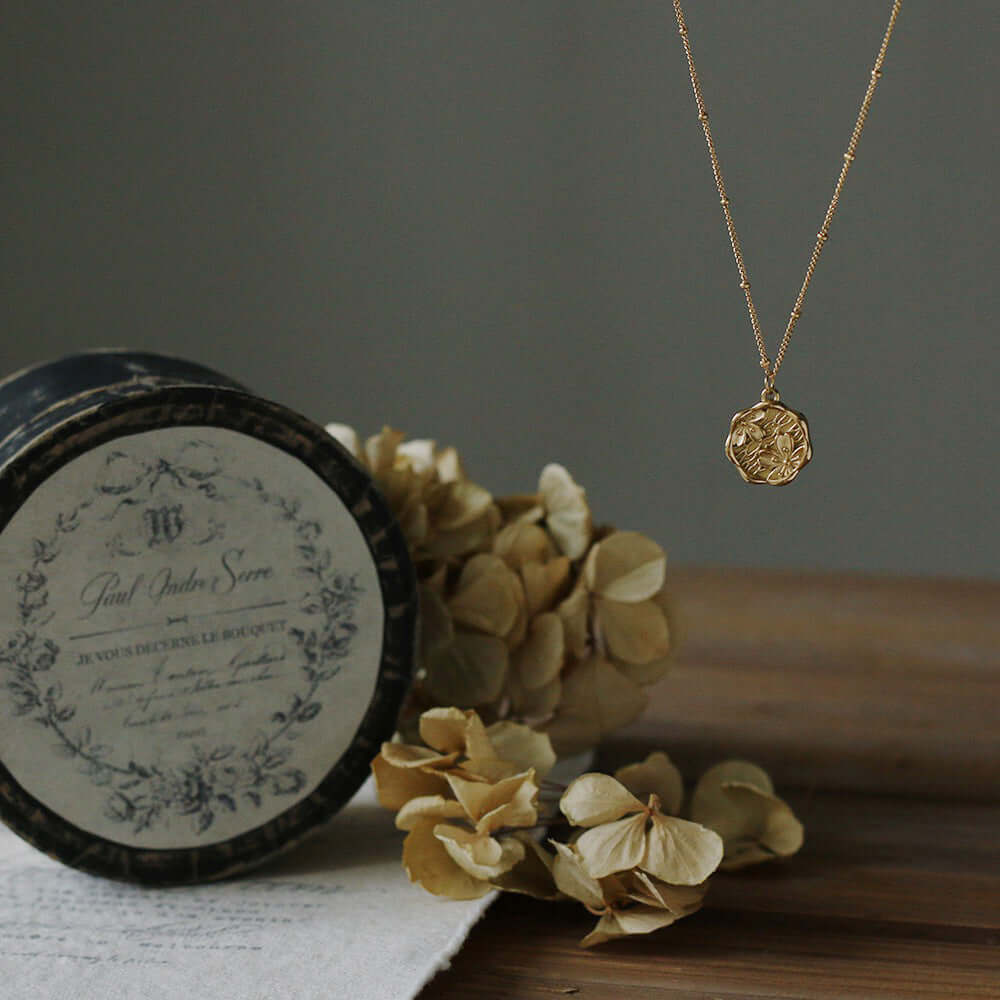 Little Miss gold medallion necklace displayed on antique box – Links & Loops Jewellery